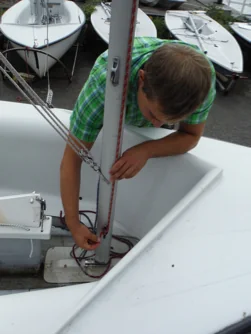 Sailor loosening a halyard at the mast