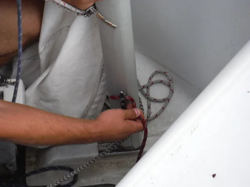 Sailor pulling the main halyard down at the mast