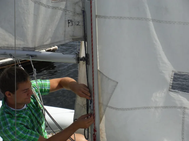 Sailor tightening the Cunningham at the mast
