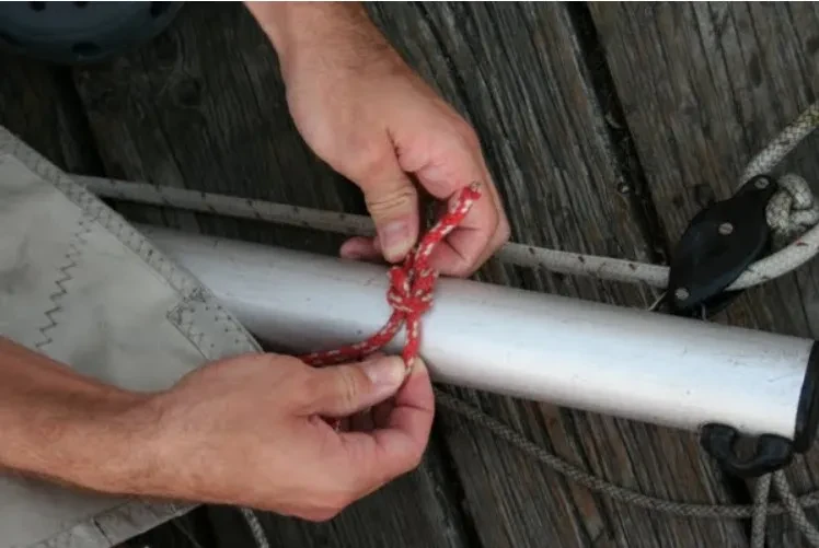 Tying the Laser clew line around the boom with a square knot.